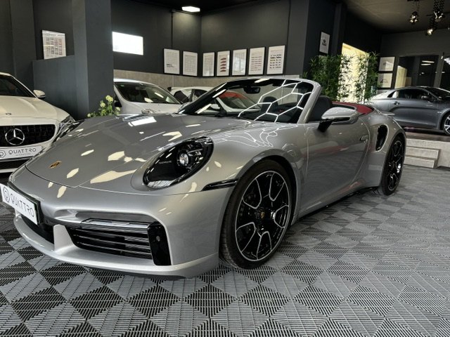A silver Porsche 911 Turbo S Cabriolet with the roof down in the showroom