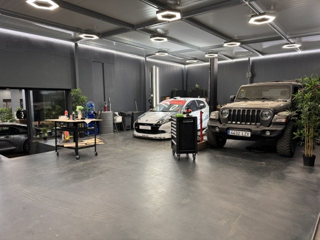 The Quattro Automotive workshop with a race car and a Jeep Wrangler under hexagonal lighting
